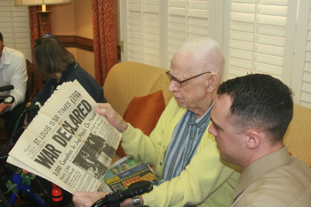 Navy veteran Clayton Bogstie, 96, shows Sgt. John Zecher, Marine Corps Intelligence Activity, an original copy of the Dec. 8, 1941 St. Louis Star-Times announcing the United States' entry into World War II. Marines visited residents of Heatherwood Retirement Community in Burke, Virginia, on Jan. 14 for coffee and conversation with the residents.