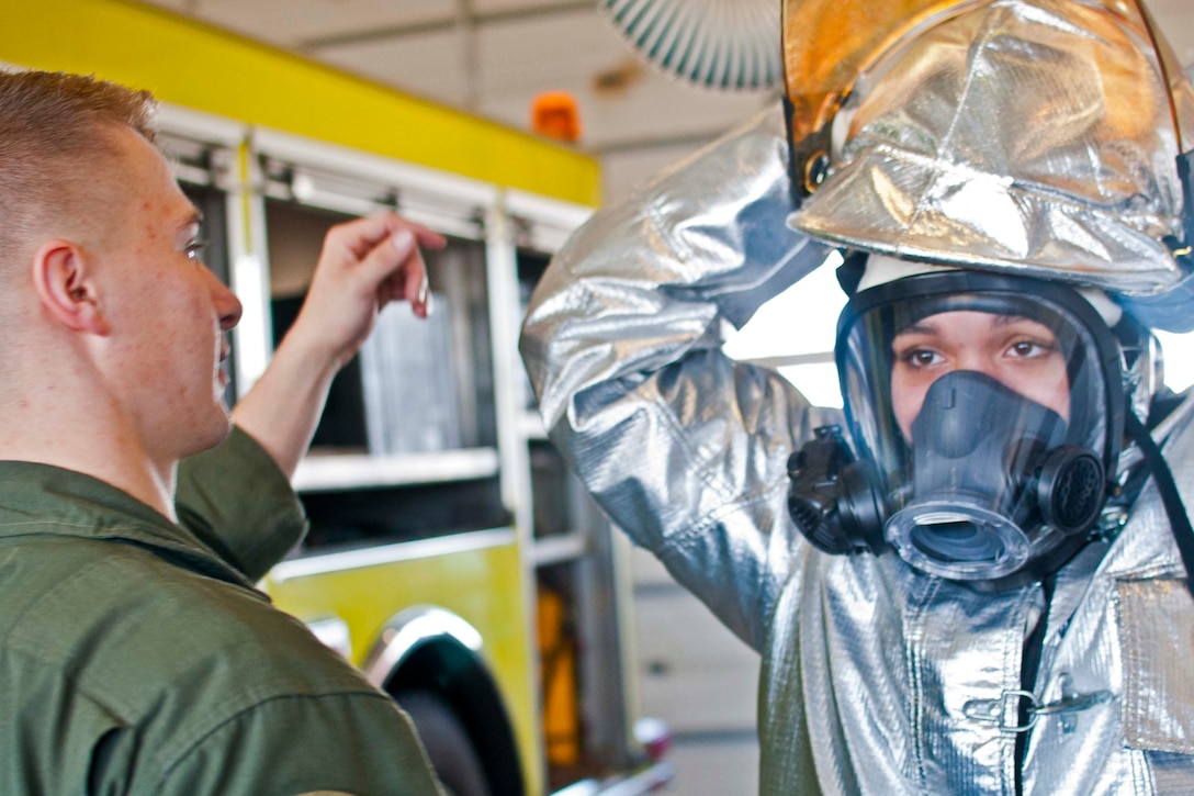Taeyah Williams, a junior at Hermitage High School, clothes herself in fireproof dress used by Air Rescue Fire Fighter during a base tour Jan. 13 aboard Marine Corps Base Quantico. The tour gave high school students first-hand experience in the military occupations filled by active duty Marines.
