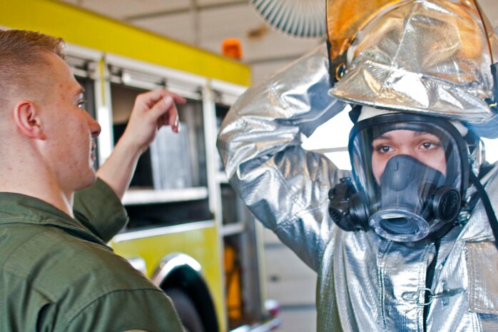Taeyah Williams, a junior at Hermitage High School, clothes herself in fireproof dress used by Air Rescue Fire Fighter during a base tour Jan. 13 aboard Marine Corps Base Quantico. The tour gave high school students first-hand experience in the military occupations filled by active duty Marines.