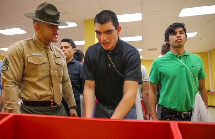 Staff Sgt. Joshua M. Cardona, drill instructor, Receiving Company, Support Battalion, instructs a new recruit to move faster during receiving at Marine Corps Recruit Depot San Diego, Jan. 19. Recruits are required to follow all instructions from drill instructors through the course of training. In the following week of receiving, they will conduct an initial strength test, undergo medical screenings and immunizations and learn the basic rules of recruit training. Annually, more than 17,000 males recruited from the Western Recruiting Region are trained at MCRD San Diego. Mike Company is scheduled to graduate April 15.
