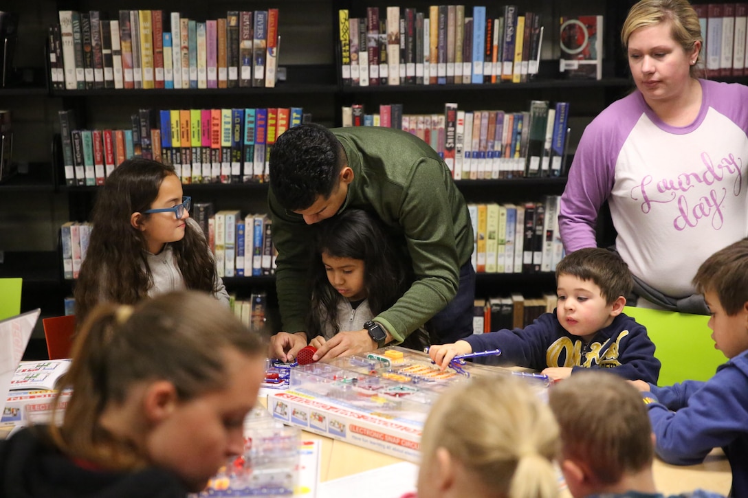 Staff Sgt. Feliz Eriel, engineer maintenance chief, Combat Logistics Battalion 7, helps his daughter Carolina, 5, assemble a snap circuit during the Combat Center Library’s Science Night, Jan. 14, 2016. The night featured stations that taught children about snap circuits, robots, magnets and X-rays. (Official Marine Corps photo Cpl. Medina Ayala-Lo/Released)