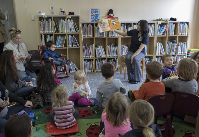 Gina Brazil-Viloria, library technician at the station library, reads a book at story time during the library open house at Marine Corps Air Station Iwakuni, Japan, Jan. 16, 2016. The open house provided an opportunity for families to explore the new sections, books and activities now available at the library. Story time attracted toddlers to the kiddie corner, the 3-D printer drew in teachers and parents, and robot cars entertained the crowd.
