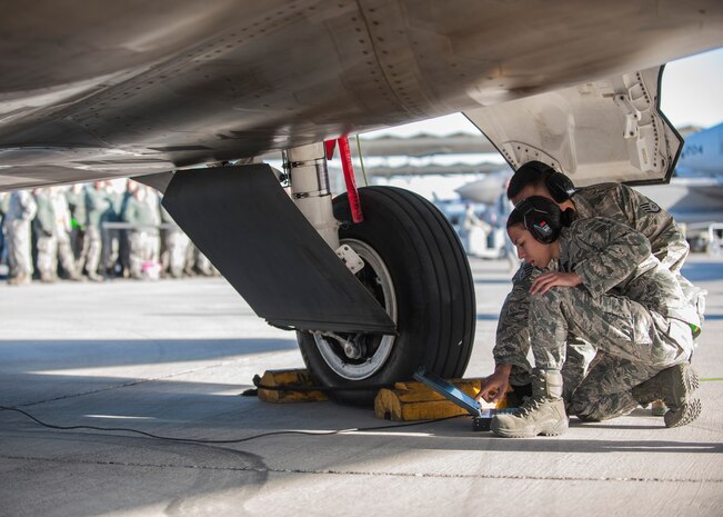 Senior Airman Jazmine Eshelman receives assistance from Staff Sgt. William Mendez in preparing an F-22 Raptor to be loaded with a munition during a quarterly weapons load crew competition at Nellis Air Force Base, Nev., Jan. 8, 2016. Eshelman and Mendez are weapons loaders assigned to Raptor Aircraft Maintenance Unit. (U.S. Air Force photo by Staff Sgt. Siuta B. Ika)