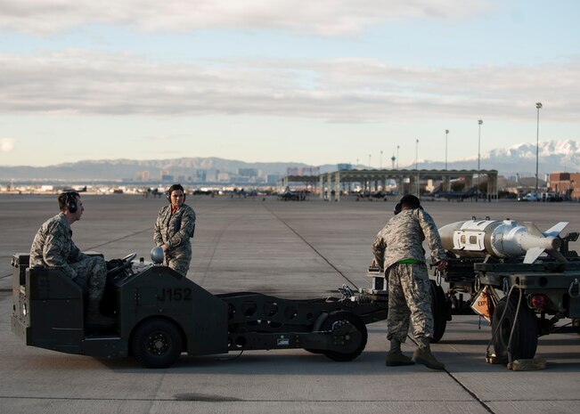 A weapons load crew from Raptor Aircraft Maintenance Unit prepares to load a munition onto an F-22 Raptor during a quarterly weapons load crew competition at Nellis Air Force Base, Nev., Jan. 8, 2016. The competitions give weapons loaders throughout the 57th Maintenance Group the opportunity to display their war-fighting skills to their peers and superiors. (U.S. Air Force photo by Staff Sgt. Siuta B. Ika)