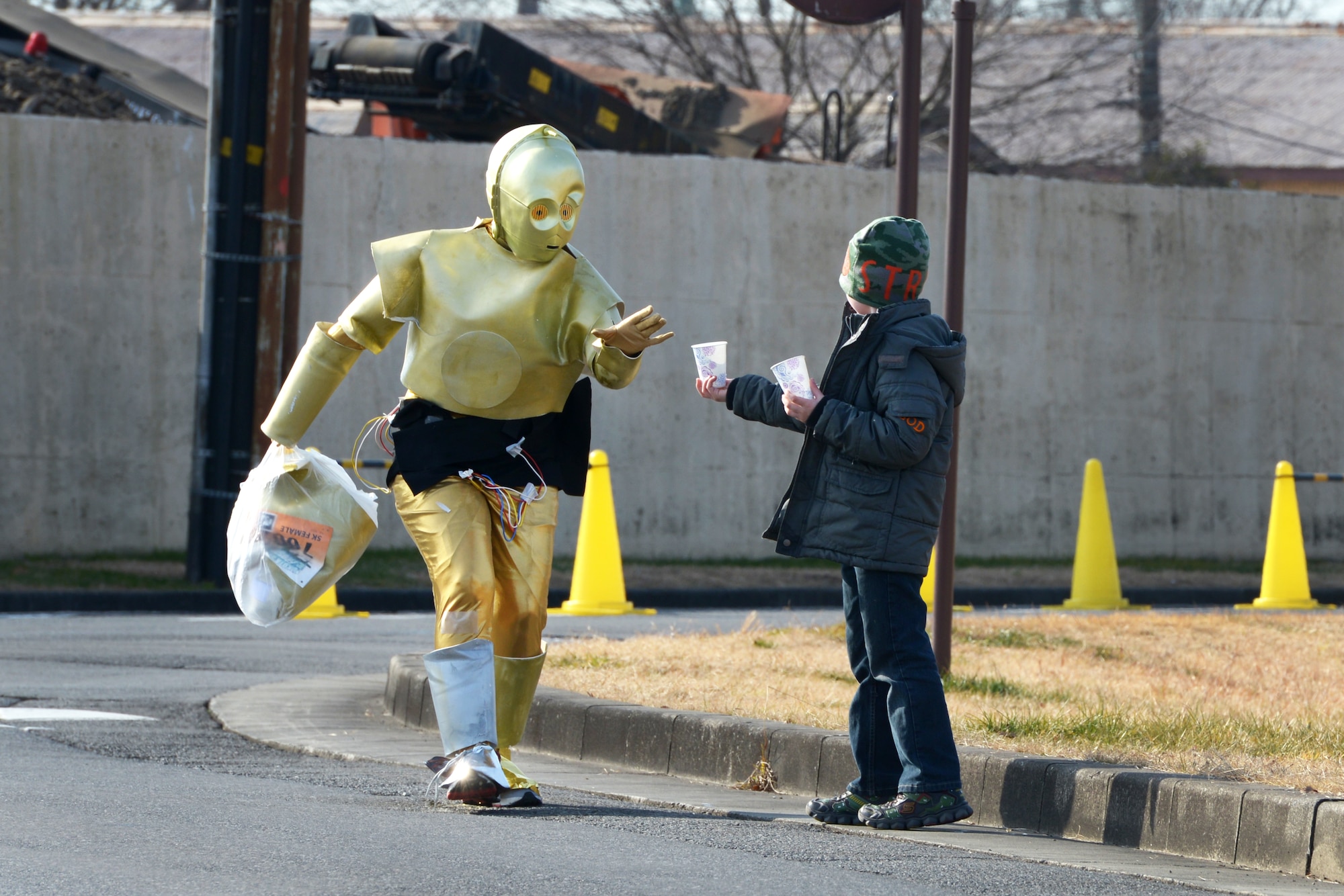 A participant dressed as C-3PO reaches for a cup of water during the 35th Annual
Frostbite Run at Yokota Air Base, Japan, Jan. 17, 2016. More than 9,000 people
participated in the annual event. Yokota hosts events throughout the year to allow
interaction between Japanese citizens and US service members and their families.
(U.S. Air Force photo by Staff Sgt. Cody H. Ramirez/Released)