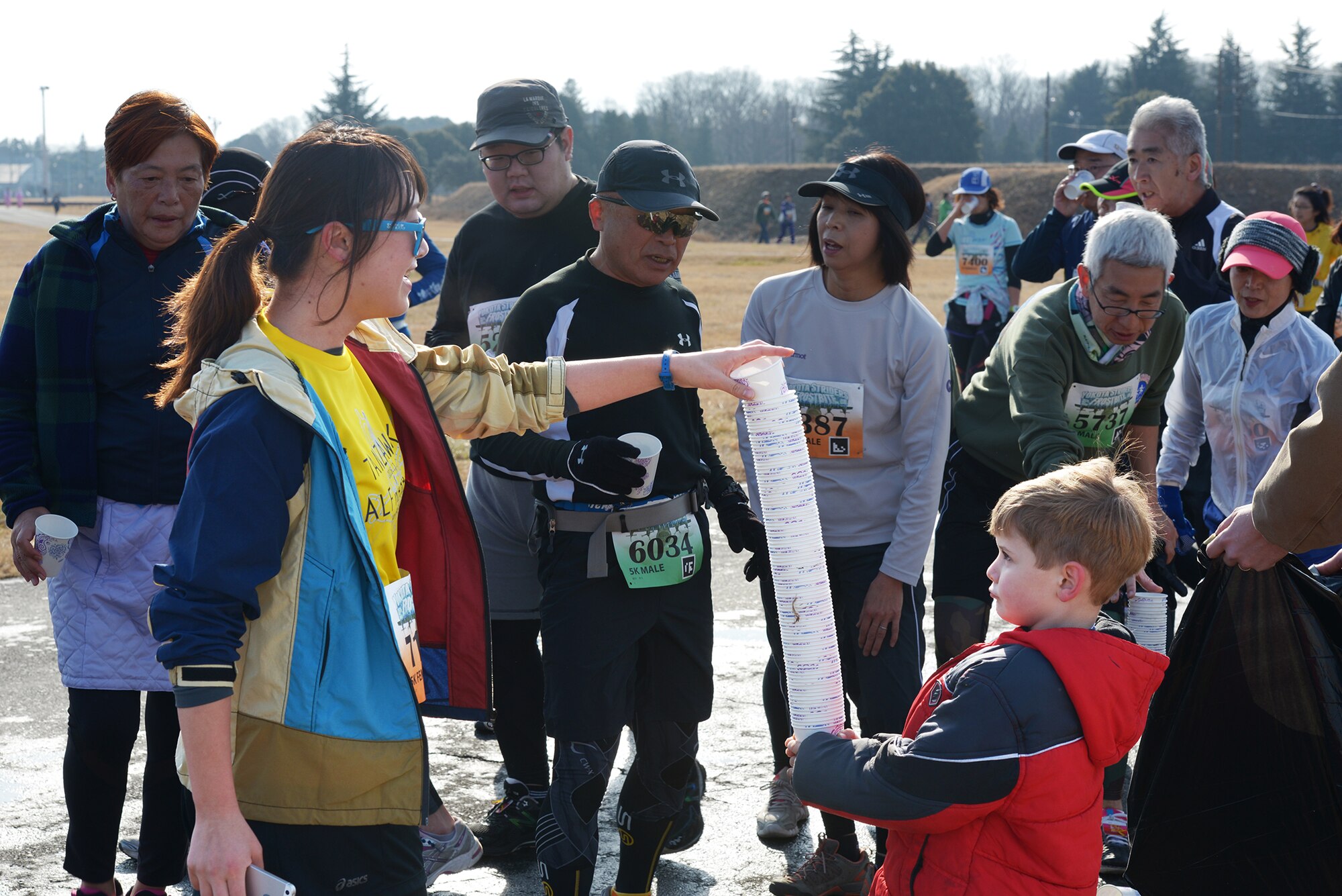 A participant gives her used water cup to a volunteer's child during the 35th Annual
Frostbite Run at Yokota Air Base, Japan, Jan. 17, 2016. Dozens of community
members at Yokota came together to make the annual event a success. (U.S. Air Force
photo by Staff Sgt. Cody H. Ramirez/Released)