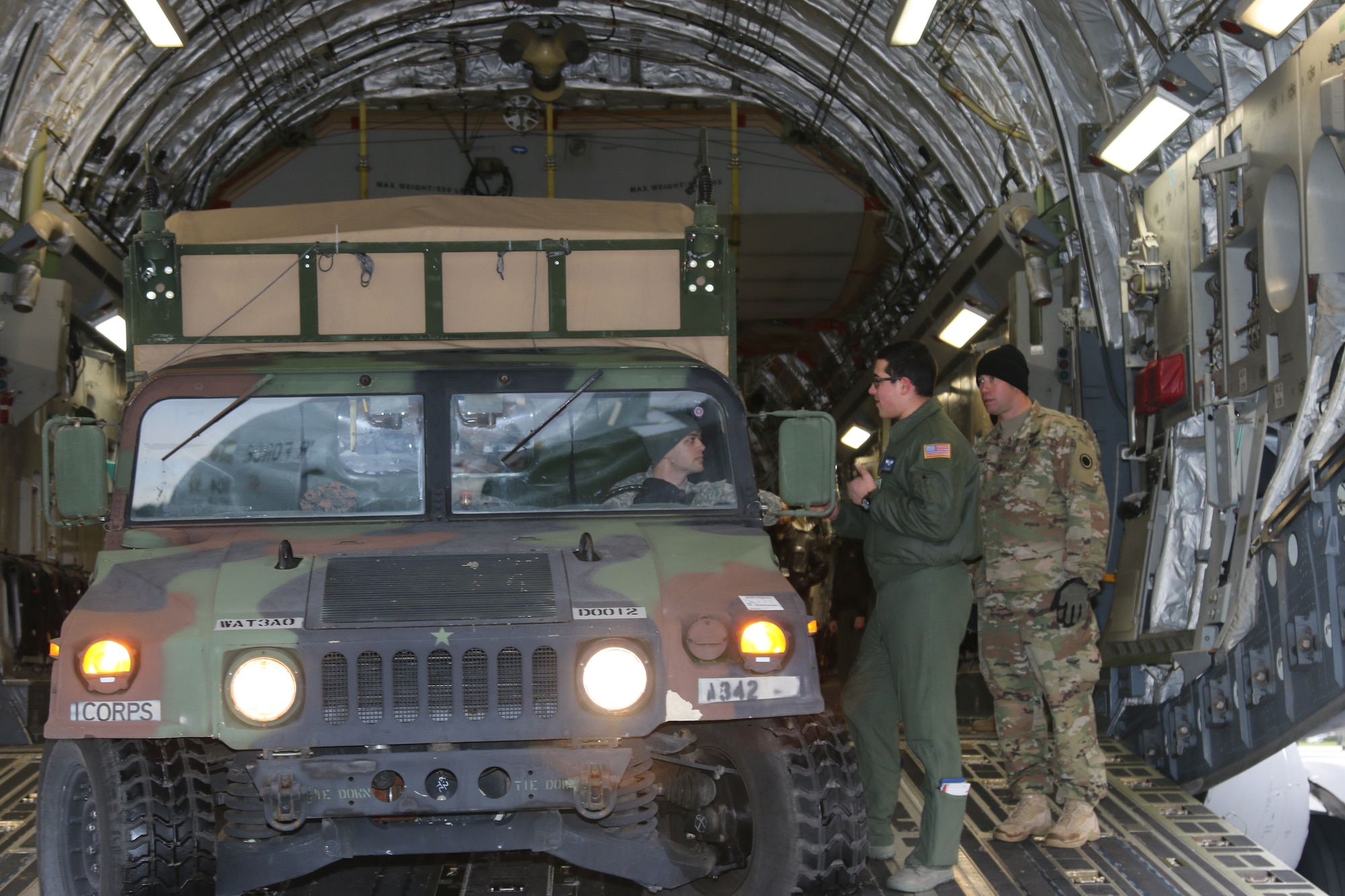 Spc. Steve Veal, a satellite communications technician with the I Corps Early Entry Command Post, confers with Airman 1st Class Zach Eye, an Airman with the 62nd Airlift Wing, on how to back into a C-17 during static load training at McChord Field Jan. 13. Three Humvees and generator trailers can fit into a single C-17. (U.S. Army photo by Sgt. Leon Cook)