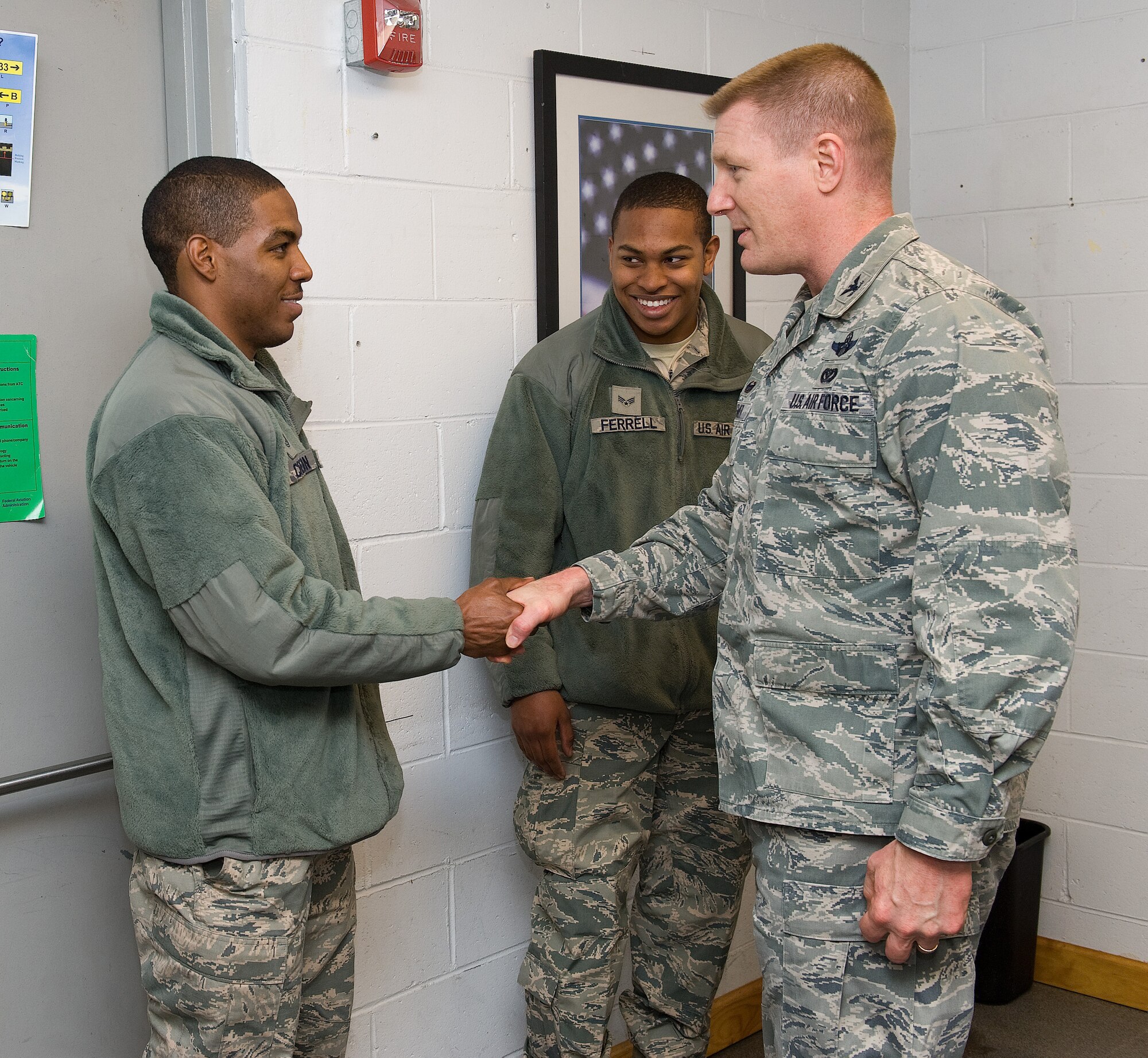 Col. Michael Grismer, 436th Airlift Wing commander, right, coins Tech. Sgt. Justin Cureton, 436th Aircraft Maintenance Squadron communication navigation technician, left, as Senior Airman Grant Ferrell, 436th AMXS crew chief, center, waits to be coined as well, Jan. 13, 2016, on Dover Air Force Base, Del. Both Cureton and Ferrell were recognized by Grismer for their outstanding work while deployed to Bagram Airfield, Afghanistan, in support of C-5M stage operations. Their efforts led to a 90.5 percent mission capable rate for transiting Super Galaxies and minimal departure delays. (U.S. Air Force photo/Roland Balik)