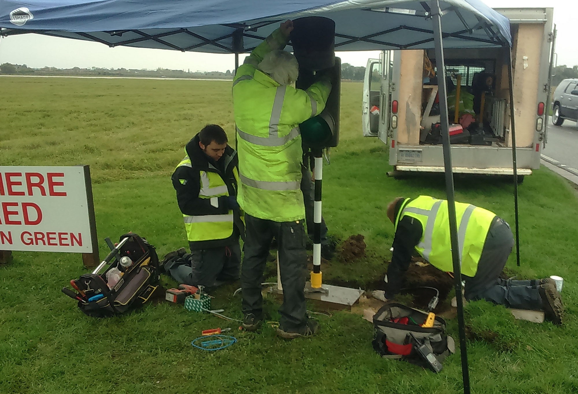 Members of the 100th Civil Engineer Squadron, work on the alignment of the new perimeter road traffic lights Nov. 5, 2015, on RAF Mildenhall, England. The airfield lighting team designed, built and implemented a raised perimeter road traffic light system to improve airfield safety. (Courtesy photo/Released)