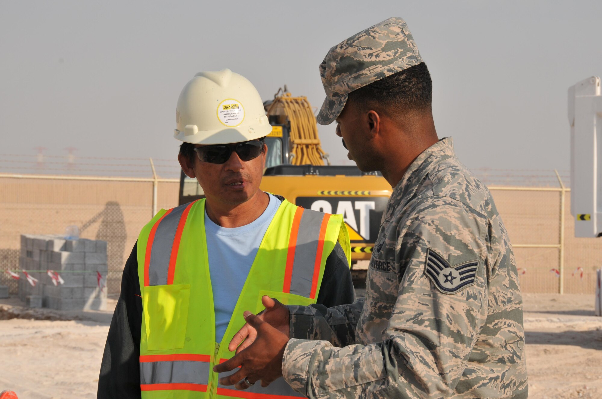 Staff Sgt. Charles Wilson, 379th Expeditionary Contracting Squadron construction contracting officer, talks with Renado, a site supervisor at a construction site Jan. 12 at Al Udeid Air Base, Qatar. Renado’s contracting team is putting up a sunshade to protect military working dogs assigned to the 379th Expeditionary Security Forces Squadron. The sunshade will protect the dogs from the sun while they are training. (U.S. Air Force photo by Tech. Sgt. Terrica Y. Jones/Released) 