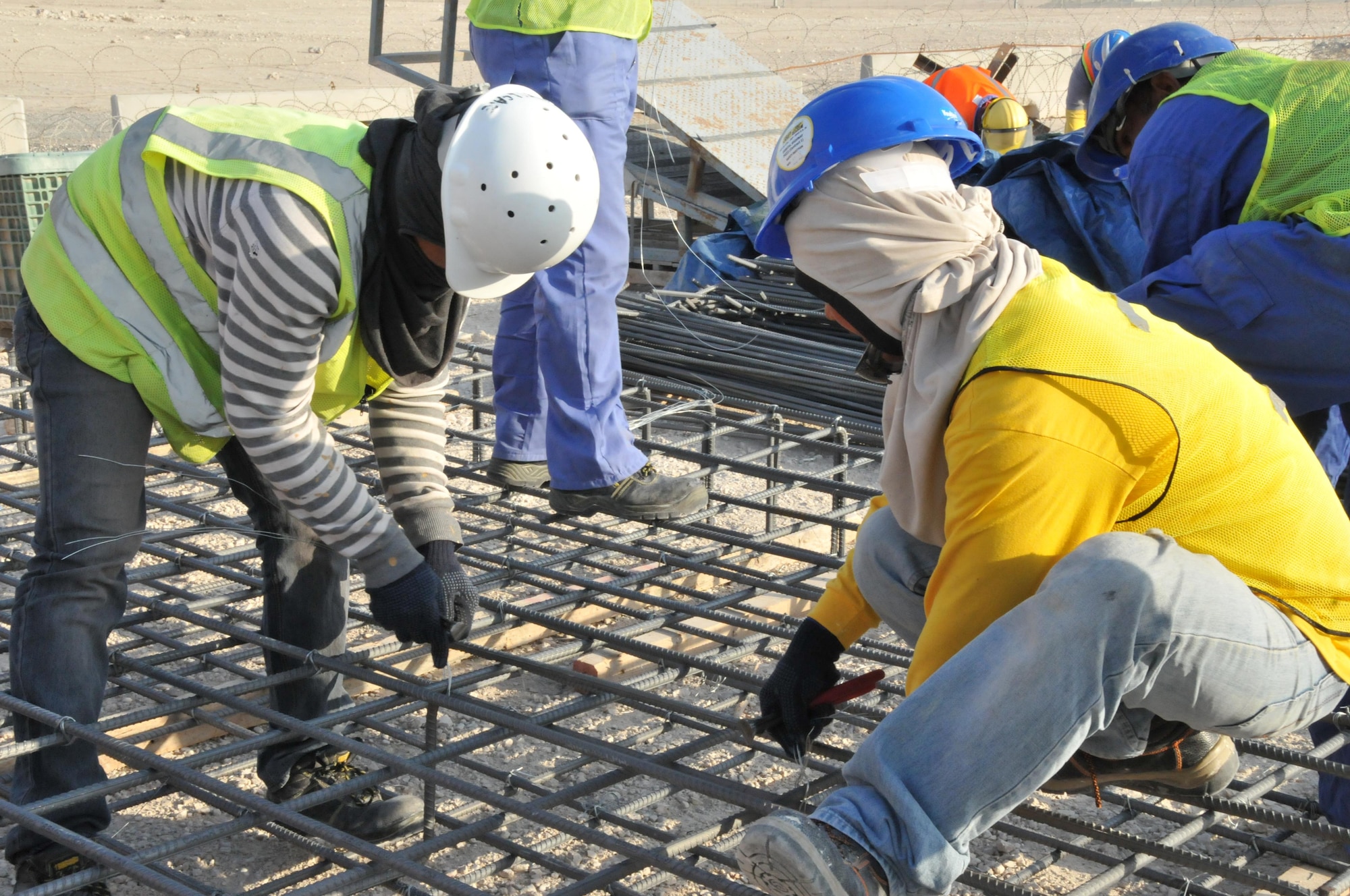 Contractors wire rebar together to support the weight of the poles for a new 379th Expeditionary Security Forces Squadron sunshade, Jan. 12 at Al Udeid Air Base, Qatar.  The rebar supports the foundation for the poles, ensuring they will not sink into the ground once the sunshade is up. Blocks will also be positioned on top of the rebar and filled with cement to help secure the sunshade’s foundation. (U.S. Air Force photo by Tech. Sgt. Terrica Y. Jones/Released)