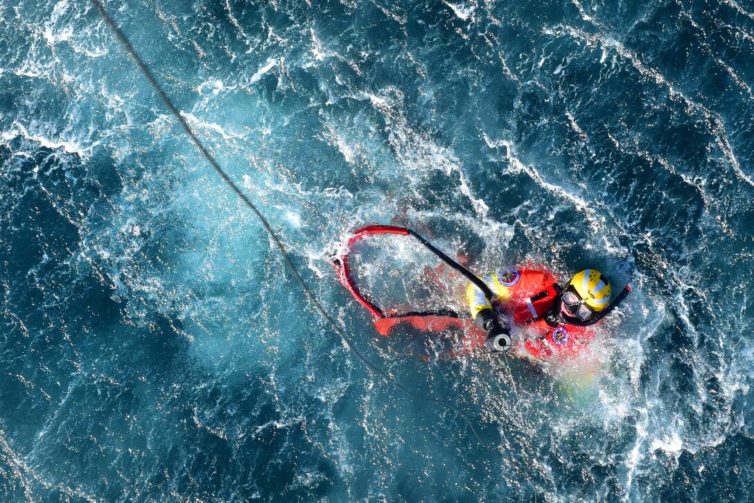 Coast Guard Petty Officer 2nd Class Kris Grimm prepares for an MH-60 Jayhawk helicopter to hoist him from the water off the coast of San Diego, Jan. 12, 2016. Grimm is an aviation survival technician assigned to Coast Guard Sector San Diego. U.S. Coast Guard photo by Petty Officer 1st Class Rob Simpson