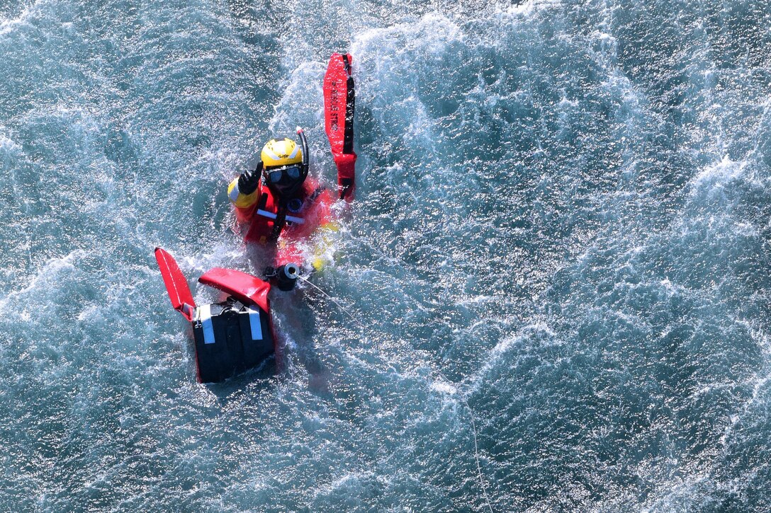 Coast Guard Petty Officer 2nd Class Kris Grimm signals for a pickup  from the water to an MH-60 Jayhawk helicopter off the coast of San Diego, Jan. 12, 2016. U.S. Coast Guard photo by Petty Officer 1st Class Rob Simpson