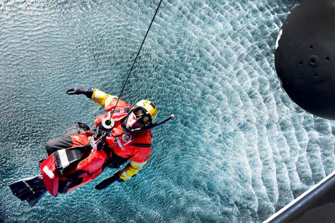 An MH-60 Jayhawk helicopter hoists Coast Guard Petty Officer 2nd Class Kris Grimm from the water off the coast of San Diego, Jan. 12, 2016. U.S. Coast Guard photo by Petty Officer 1st Class Rob Simpson
