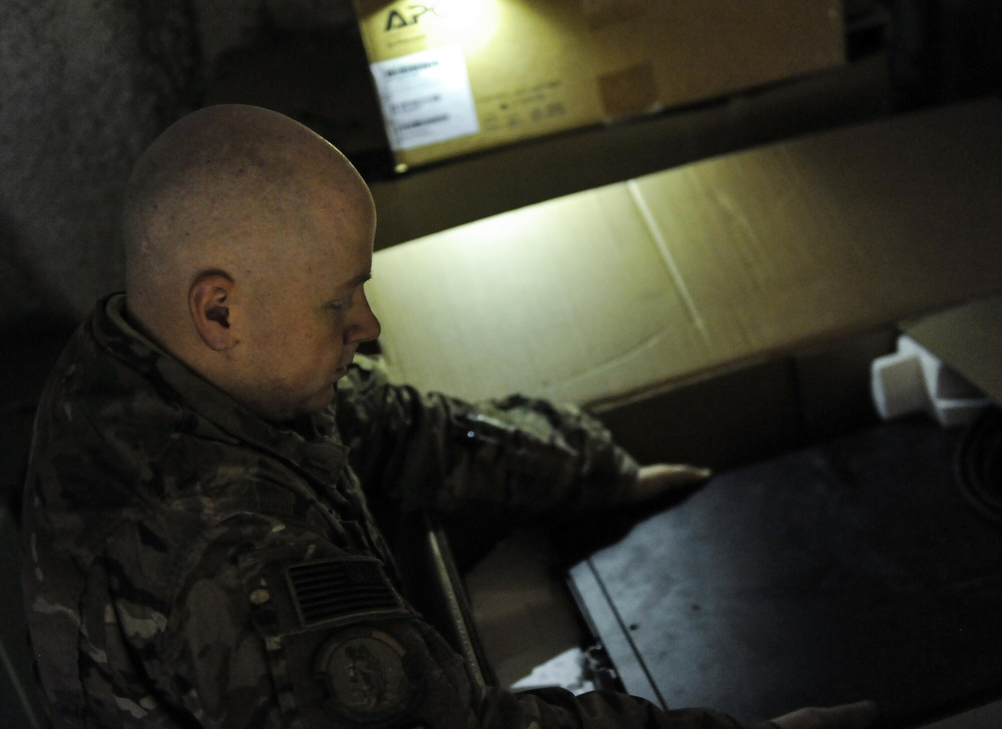 Staff Sgt. Patrick Little, 455th Expeditionary Communications Squadron cyber transport supervisor, removes a back-up power supply from a darkened storage area at Bagram Airfield, Afghanistan, Jan .13, 2016. The Network Management section is tasked with installing and maintaining the physical assets inside the building. (U.S. Air Force photo by Tech. Sgt. Nicholas Rau)    