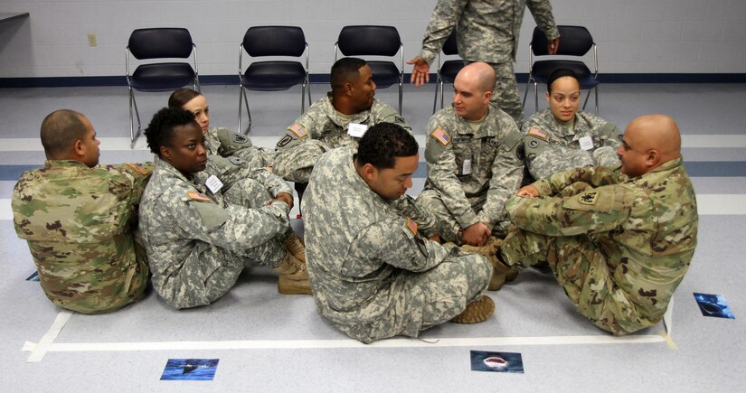 U.S. Army Reserve Sgt. Lionel P. Brown, 314th Military Police Company, 11th Military Police Brigade, 200th Military Police Command, center, seems to determine "how close a shark is to his sinking lifeboat" during the Life Raft Exercise of the Equal Opportunity Leaders Course 16-01 hosted by the 84th Training Command at the 11th Theater Aviation Command's Headquarters on Fort Knox, Ky., Nov. 18, 2015. (U.S. Army photo by Clinton Wood/Released).