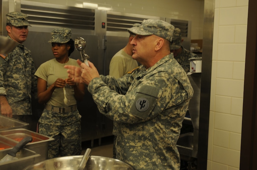 Chief Warrant Officer 2 Danny Wolf, 103rd Sustainment Command (Expeditionary) and Army Reserve Culinary Arts Team coach, demonstrates a cooking technique during a training session in Sloan, Nev.