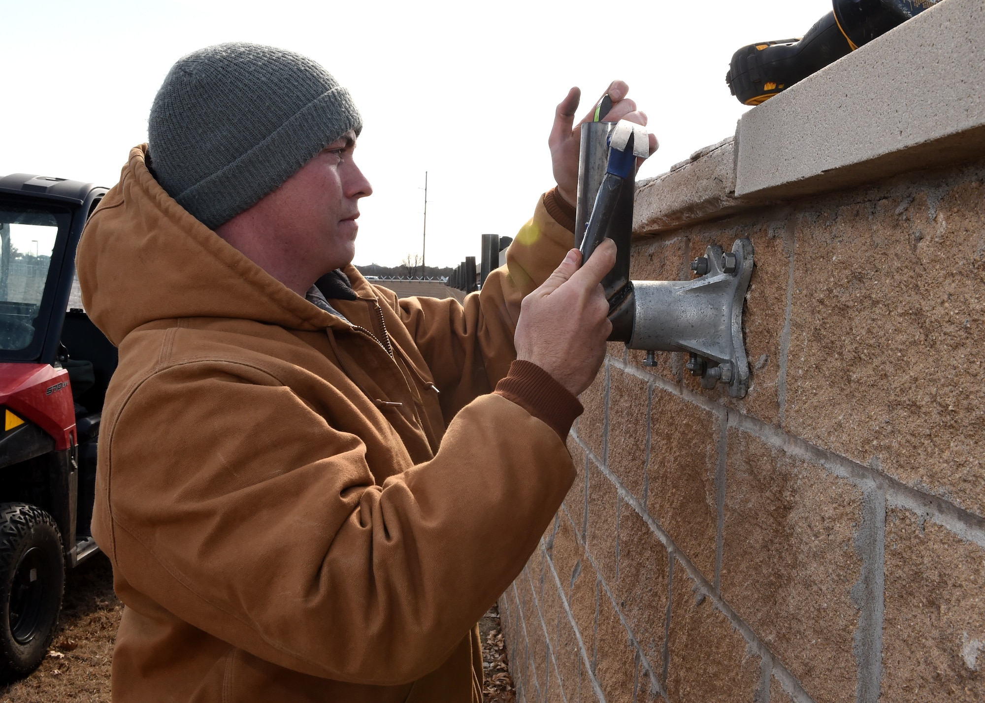 U.S. Air Force Senior Airman Chad Chapman, 97th Civil Engineer Squadron structural journeyman, secures wall anchors to the perimeter wall near base housing, Jan. 19 at Altus Air Force Base, Okla. Members of the 97th Civil Engineer Squadron and the 97th Security Forces Squadron teamed up to improve base security by installing additional force protection measures along 3,200 feet of the base’s perimeter fence.