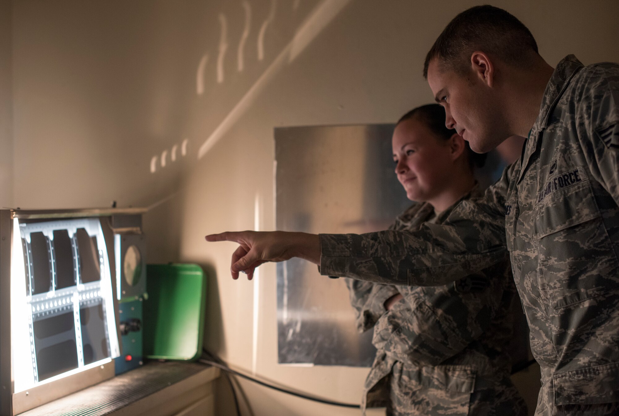 Staff Sgt. Matthew Barnes, 366th Equipment Maintenance Squadron non-destructive inspections craftsman, explains what he's looking for in the x-ray to Senior Airman Violette Zeimet, 366th EMS NDI journeyman, Jan. 15, 2016, at Mountain Home Air Force Base, Idaho. NDI uses radiographic inspection to find cracks or defects deep within various parts of the aircraft.(U.S. Air Force photo by Senior Airman Jeremy L. Mosier/Released)