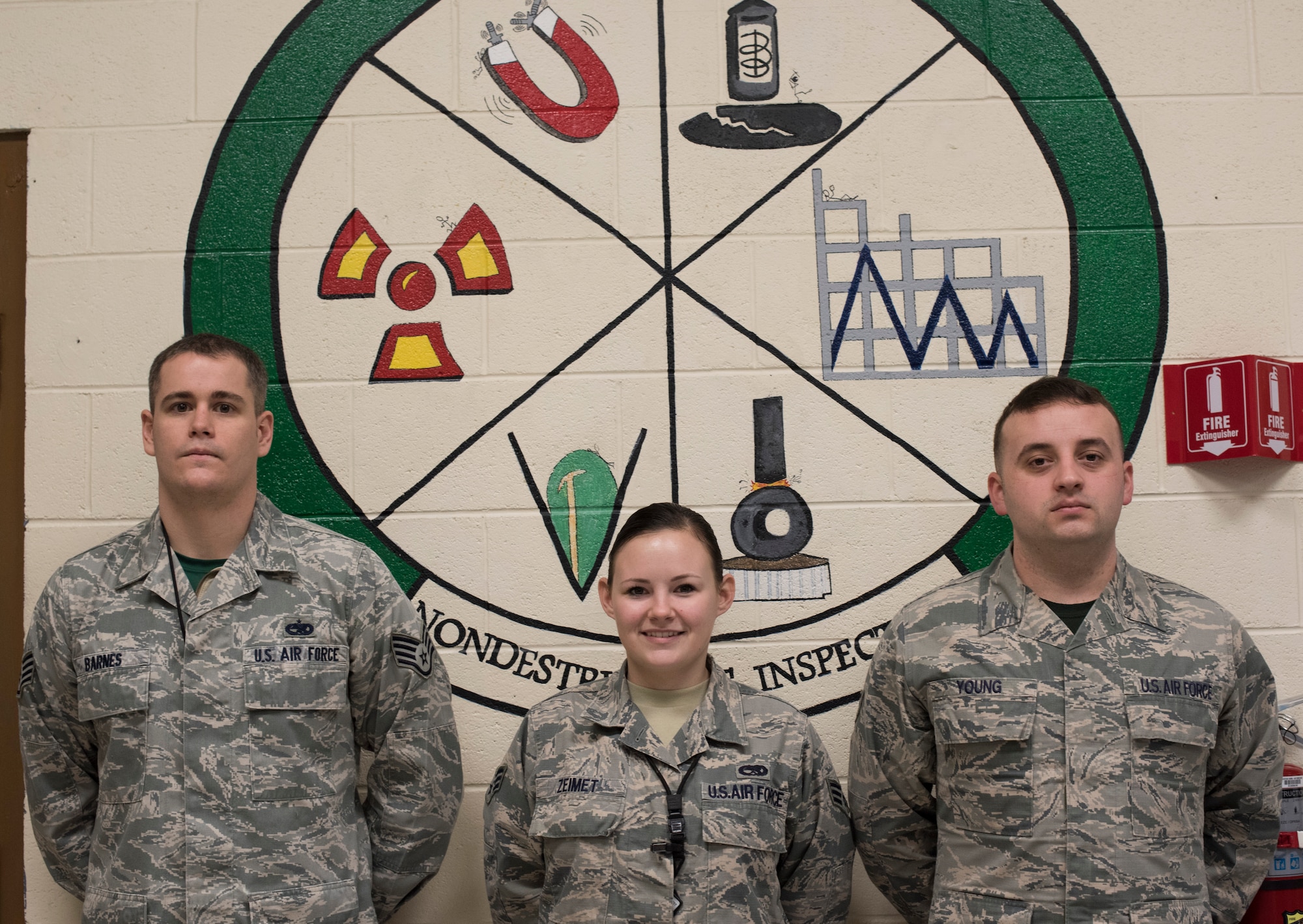 From left to right:  Staff Sgt. Matthew Barnes, 366th Equipment Maintenance Squadron non-destructive inspections craftsman, Senior Airman Violette Zeimet, 366th EMS NDI journeyman, and Senior Airman Phillip Young, 366th EMS NDI journeyman, pose for a photo in front of their occupational crest Jan. 15, 2016, at Mountain Home Air Force Base, Idaho.  NDI personnel must be proficient in identifying metals, metals' flaws and have a strong understanding of radiological safety.(U.S. Air Force photo by Senior Airman Jeremy L. Mosier/Released)