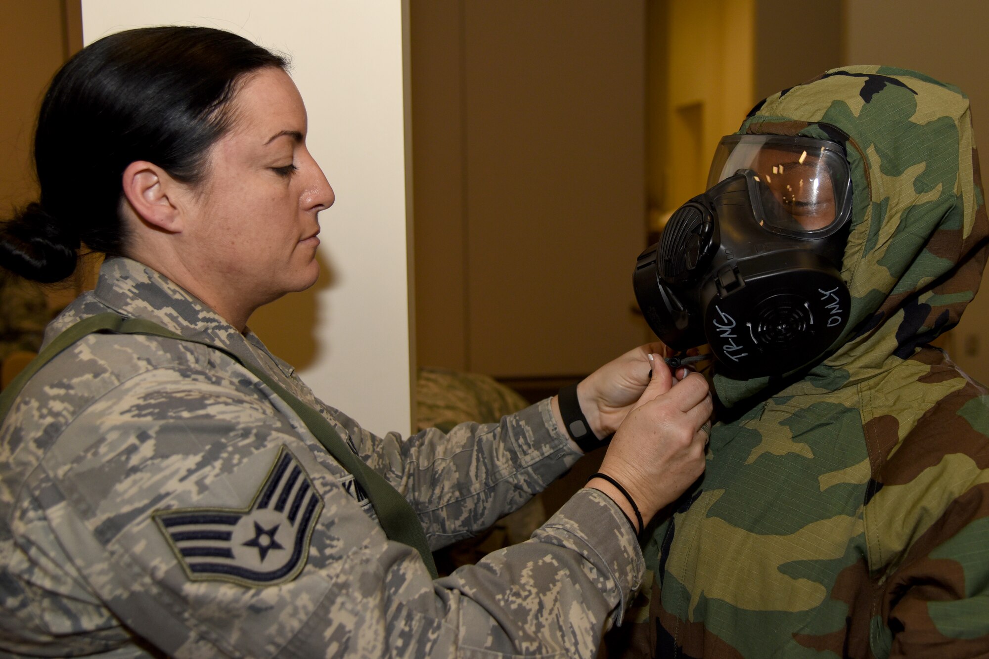 Staff Sgt. Tiffany Skinner aides Senior Airman Kazardra Berry, both of whom are personnelists with the 403rd Force Support Squadron, with tightening her hood around her mask during training at the Roberts Consolidated Maintenance Facility here Monday. The training was part of the 403rd Wing’s Exercise Agile Sabre Jan. 11-15, 2016 at Keesler Air Force Base, Mississippi. (U.S. Air Force photo/Staff Sgt. Nicholas Monteleone)