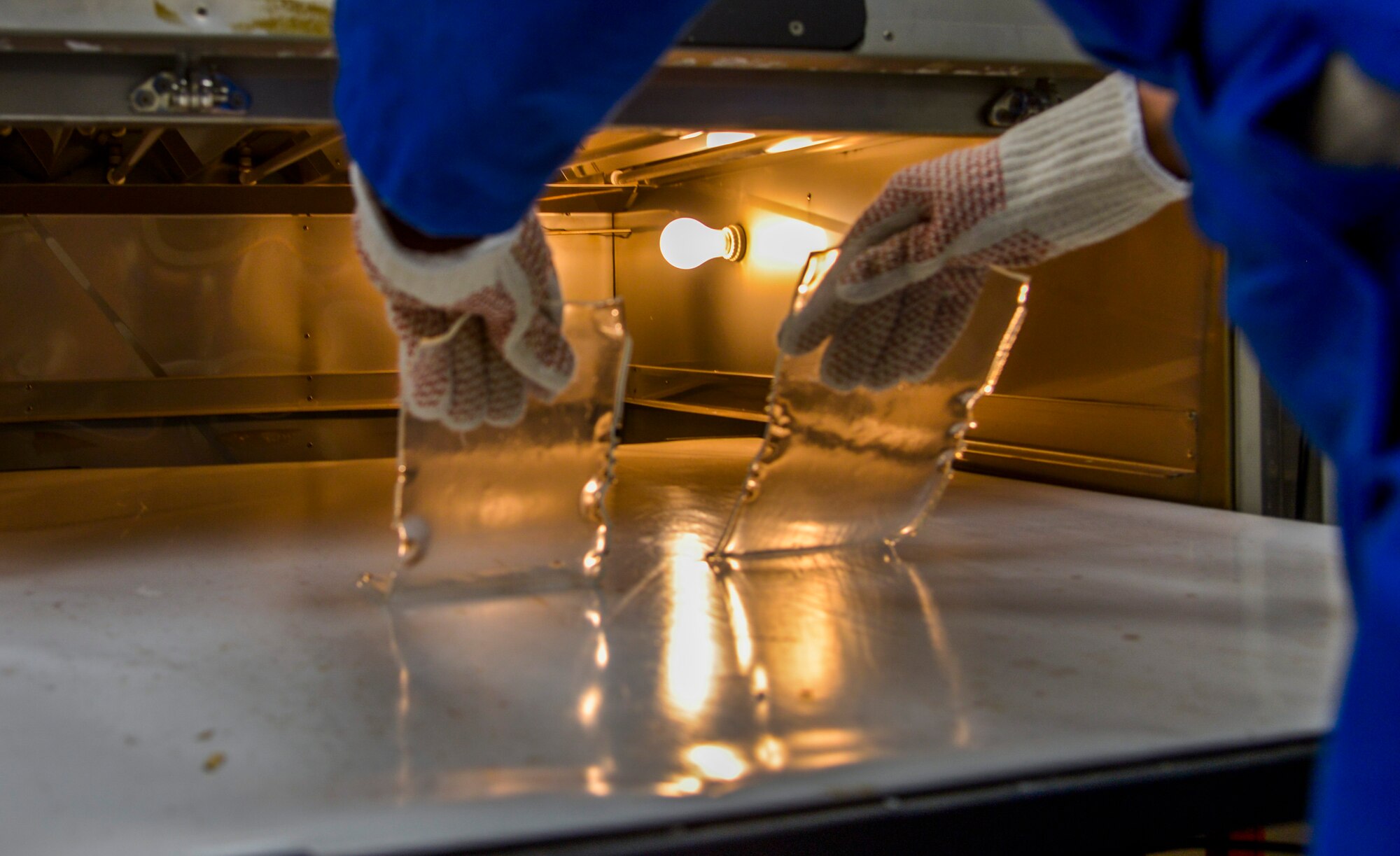 Tech. Sgt. Joy Victoria, 374th Surgical Operations Squadron orthotics NCO in charge, takes polypropylene plastic inserts out of an oven at Yokota Air Base, Japan, Jan. 20, 2016. The oven needs to heat up to 400 degrees to soften the plastic to be molded into shoe inserts. Inserts can be helpful for a variety of foot ailments, including flat arches, high arches, and foot and leg pain. (U.S. Air Force photo by Senior Airman David Owsianka/Released)