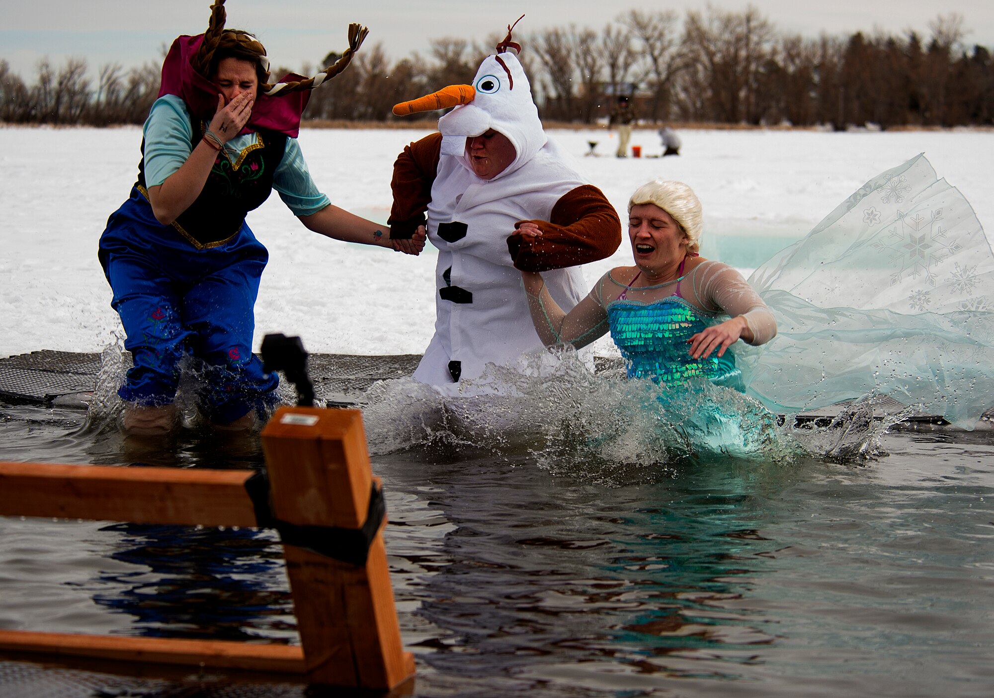 Katie Emmons, Erica Cushmore and Jenny Hall appropriately make the leap in the frozen Sloan Lake in Cheyenne, Wyo., wearing costumes from the movie “Frozen” January 11, 2015. They were taking part in the fourth-annual Matthew S. Schwartz Memorial Polar Plunge, which raised money for the Explosive Ordinance Disposal Warrior Foundation, a program that offers financial help to the families of EOD veterans who have been injured or killed in action. (U.S. Air Force photo by R.J. Oriez)