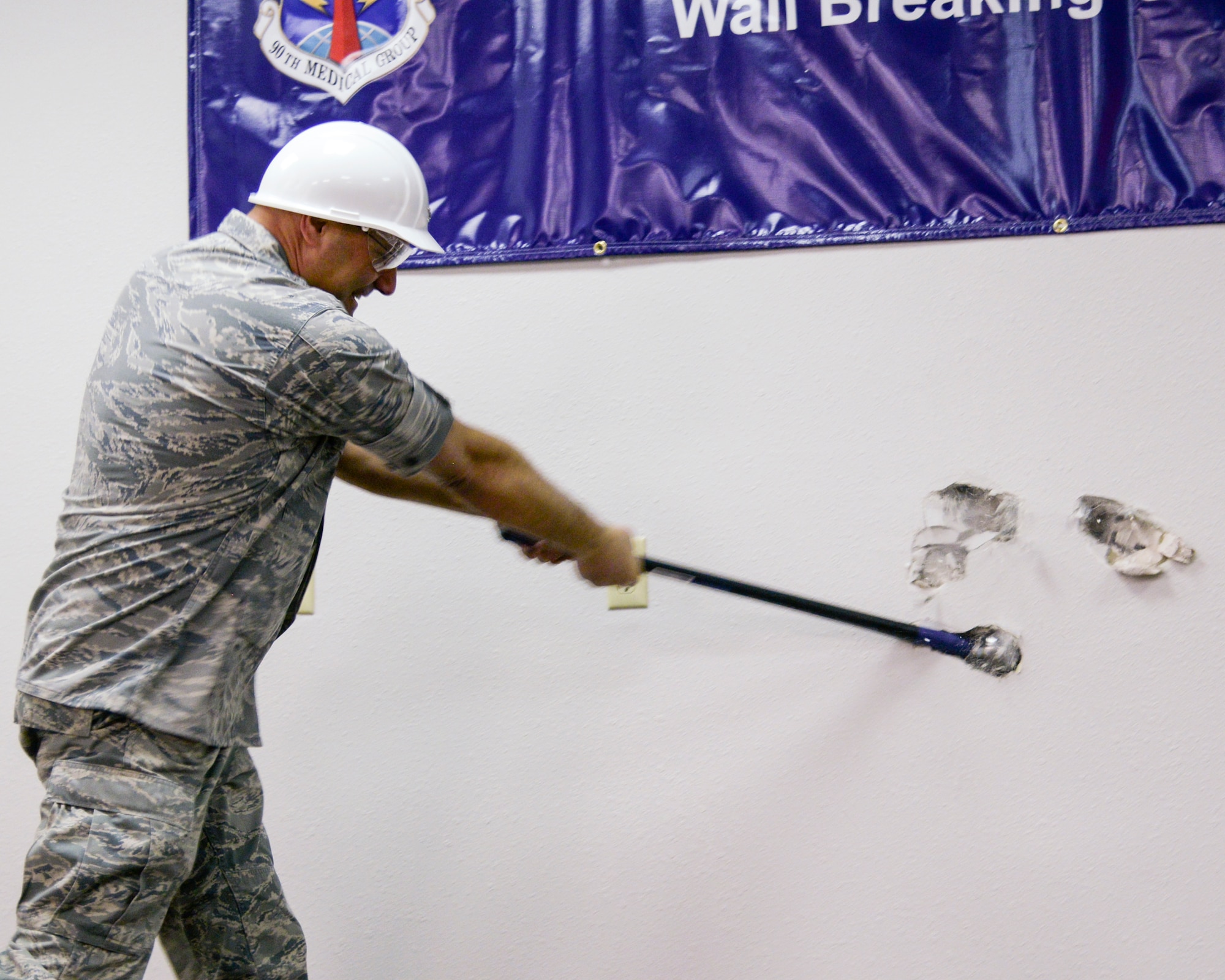 Col. Stephen Kravitsky, 90th Missile Wing commander, takes a swing during at a wall in the 90th Medical Group Medical Treatment Facility during a ceremony Jan. 19, 2015, on F.E. Warren Air Force Base, Wyo. Actual construction is scheduled to begin February and will make the MTF more patient-friendly and efficient. (U.S. Air Force photo by Airman 1st Class Malcolm Mayfield)