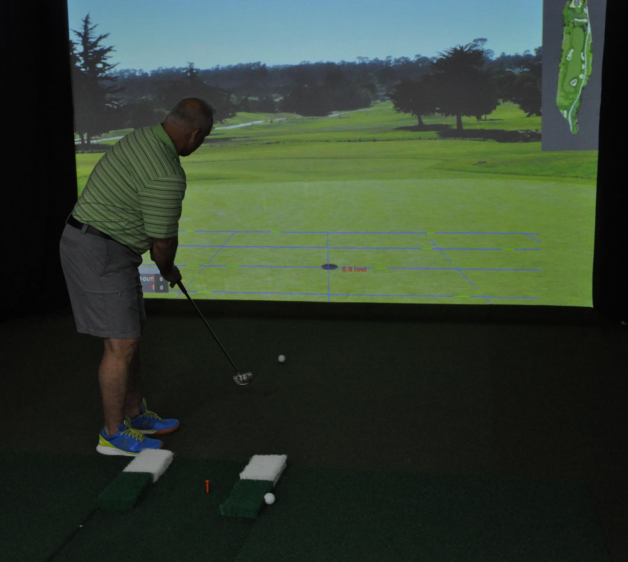Retired Chief Master Sgt. Joey McCoy attempts to sink a put while playing a round of golf with the high definition golf simulator inside the Blatchford Preston Complex Community Activity Center at Al Udeid Air Base, Qatar, Jan. 16. McCoy said he enjoys playing golf and the simulator provides golfers with a realistic golfing experience. The simulator offers practice and competition modes, as well as one-on-one instruction from a virtual golf coach. (U.S. Air Force photo by Tech. Sgt. James Hodgman)