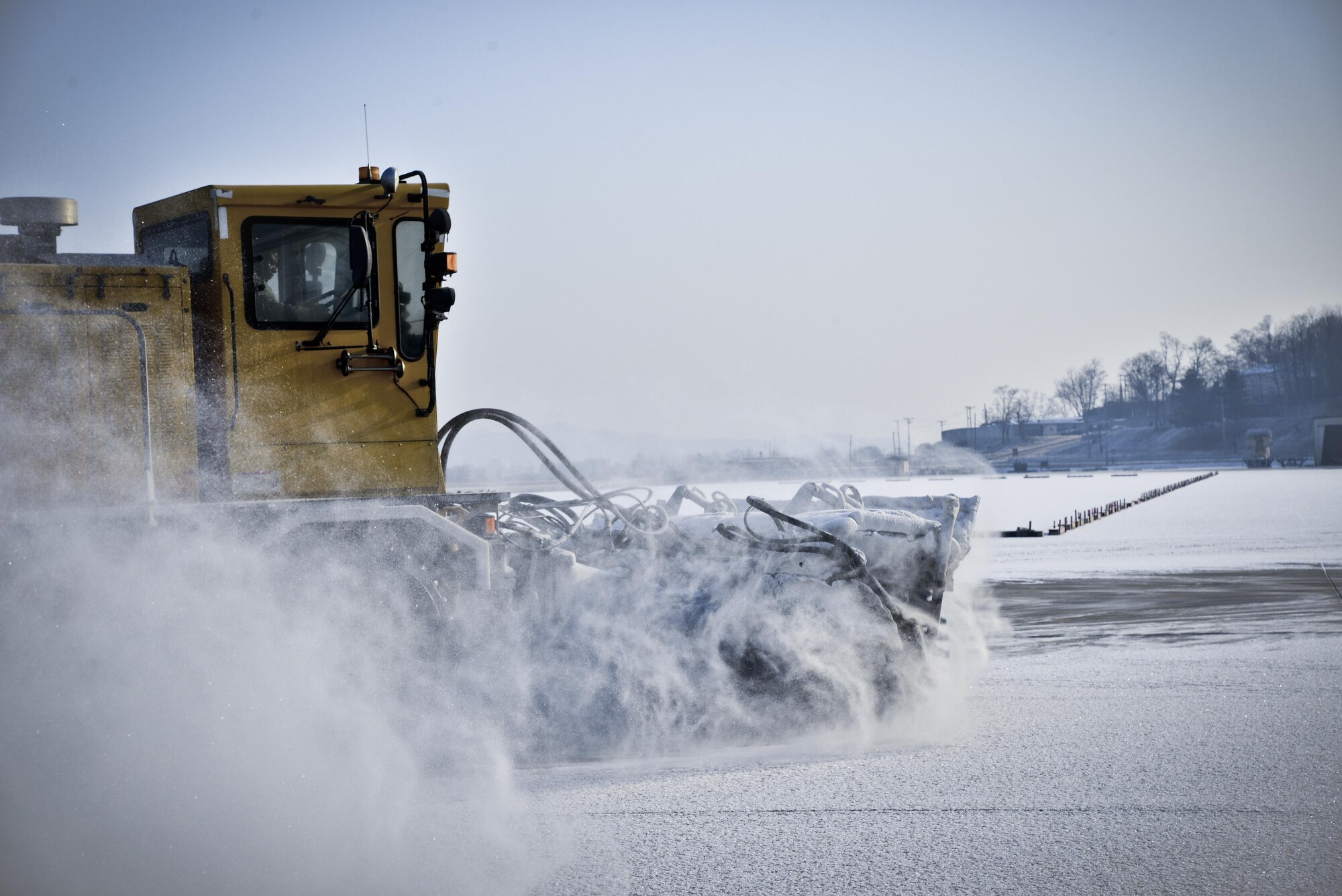 An Airman from the 51st Civil Engineer Squadron uses a runway sweeper truck to remove the first snow of the year on the flightline behind the Air Mobility Command passenger terminal Jan. 13, 2016, at Osan Air Base, South Korea. Airmen remove snow from the runways, taxiways and flightline to ensure passenger and aircraft safety. The runway sweeper head is approximately 20-feet wide, which helps reduce the amount of time it takes to completely clear the flightline of snow. (U.S. Air Force photo/Tech. Sgt. Travis Edwards)