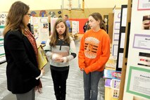 Carol Elder, Huntsville Center's Interior Design chief, listens as fifth-graders Kirsten Goodenought and Ashlyn Harris explain how saltwater makes gummy bears shrink during the Challenger Elementary School Science Fair Jan. 20.