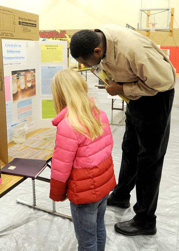 Juan Pace, a technical manager for the Huntsville Center’s Facilities Repair and Renewal Program, bends down to hear third-grader Lauren Todd’s explanation of how different temperatures affect the growth of crystals during the Challenger Elementary School Science Fair Jan. 20. 