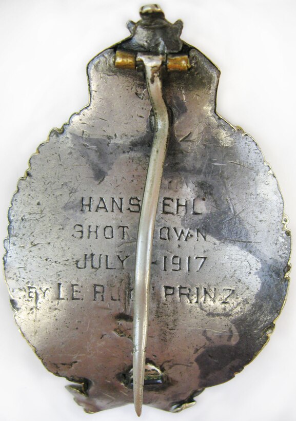 At the outbreak of World War I, LeRoy J. Prinz went to France to train as a pilot. Initially, he served in the French Aviation Corps, then with the 94th Aero Squadron and the 27th Aero Squadron. This aviator pin has a front design of a wreath with bow at bottom and a triptych crown at top. Centered within the wreath opening is a scene of an aircraft flying over mountains, fields and buildings in Europe. The back is engraved: HANS EHL,  SHOT DOWN,  JULY 1 1917,  BY LE ROY PRINZ (U.S. Air Force photo)