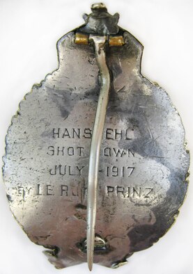 At the outbreak of World War I, LeRoy J. Prinz went to France to train as a pilot. Initially, he served in the French Aviation Corps, then with the 94th Aero Squadron and the 27th Aero Squadron. This aviator pin has a front design of a wreath with bow at bottom and a triptych crown at top. Centered within the wreath opening is a scene of an aircraft flying over mountains, fields and buildings in Europe. The back is engraved: HANS EHL,  SHOT DOWN,  JULY 1 1917,  BY LE ROY PRINZ (U.S. Air Force photo)