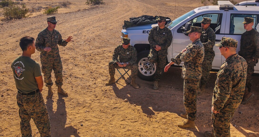 Chief Warrant Officer 3 John Hermann (top left), the officer-in-charge of Headquarters and Headquarter Squadron’s explosive ordnance disposal unit, based out of Marine Corps Air Station Yuma, debriefs his Marines after completing a training exercise at the Barry M. Goldwater Range in Yuma, Ariz., Tuesday, Dec. 8, 2015.