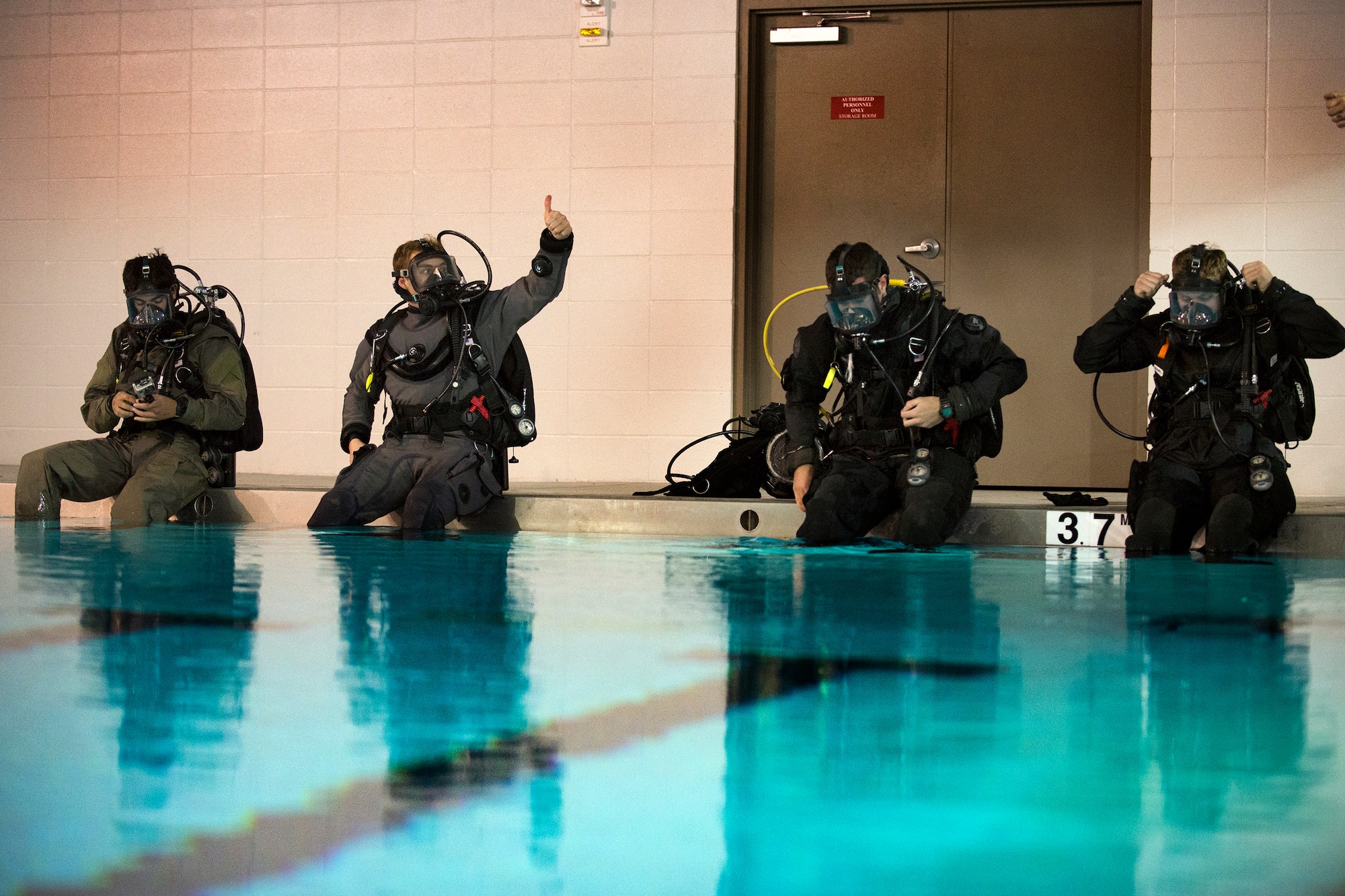 Airmen from the 38th Rescue Squadron make final adjustments to their gear before diving into the pool, Jan. 20, 2016, at Moody Air Force Base, Ga. Rescue Airmen train in diving two to three times throughout the year, but must qualify annually. (U.S. Air Force photo by Airman Daniel Snider/released)