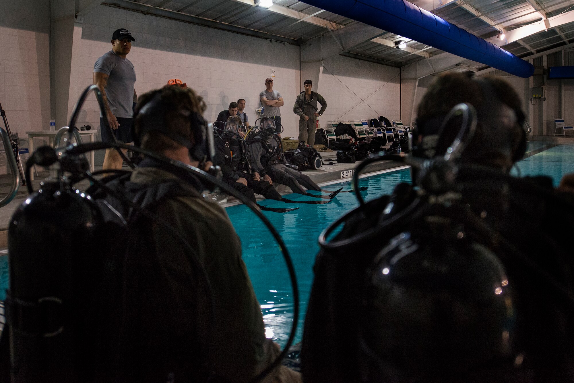 Airmen from the 38th Rescue Squadron watch as a group of pararescuemen prepare to plunge into the pool, Jan. 20, 2016, at Moody Air Force Base, Ga. Rescue Airmen train in wetsuits and drysuits to ensure they are prepared for any water rescue mission. (U.S. Air Force photo by Airman Daniel Snider/released)