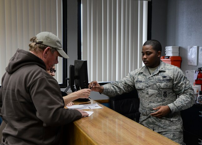 Airman 1st Class Alonzo Pittman, 99th Security Forces Squadron visitor center control technician, assists visitors with getting a base pass in the Visitor Center at Nellis Air Force Base, Nev., Jan. 19, 2016. The Visitor Center is located at the main gate and is open 24/7. (U.S. Air Force photo by Airman 1st Class Nathan Byrnes)