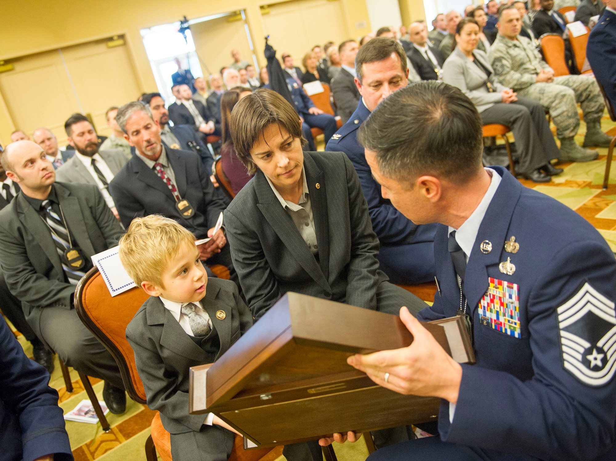 Chief Master Sgt. Anthony Bechtold, Special Agent with the Air Force Office of Special Investigations, presents a shadow box to Maj. Vorderbruggen’s wife and son, Heather and Jacob, during a memorial service for Vorderbruggen at the Soundside on Hurlburt Field, Fla., Jan. 21. Vorderbruggen was a special agent assigned the OSI squadron located on Eglin Air Force Base, Fla.  She was killed in action Dec. 21, 2015 during a deployment to Bagram Airfield, Afghanistan. (U.S. Air Force photo by Senior Airman Krystal M. Garrett) 