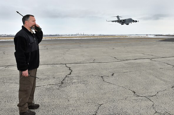 Blaine Barnett, 62nd Operations Support Squadron operations support specialist, talks to a 62nd Airlift Wing C-17 Globemaster III on approach to Grant County International Airport, Wash., assault runway Jan. 15, 2016. Barnett a.k.a. the Iron Cross and his team support all of the assault zone operations east of the cascades for the 62nd AW. (U.S. Air Force photo/ Senior Airman Naomi Shipley)