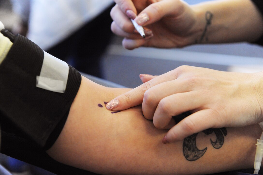 A collection specialist with the American Red Cross marks a donor’s arm as part of the donation process during a blood drive at Whiteman Air Force Base, Mo., Jan. 13, 2016. The blood donation is a four-step process: registration, medical history and mini-physical, followed by the donation.  Each donation of 1-pint can contribute to saving up to 3 lives. (U.S. Air Force photo by Tech. Sgt. Miguel Lara III)