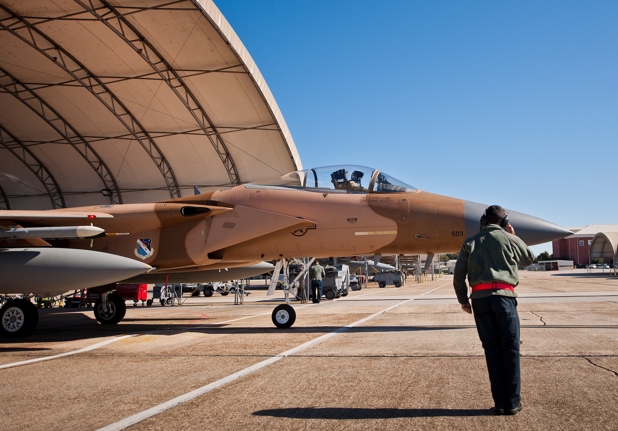 Senior Airman Oscar Mares, 96th Aircraft Maintenance Squadron, salutes the pilot of an F-15 Eagle as it taxies out for a sortie Jan. 20 at Eglin Air Force Base, Fla.  The camouflage aircraft is the only one painted this way on the base. Its Jan. 20 sortie marked the last time it would fly with that paint scheme before being returned to the traditional gray.  The F-15 was painted that way for its role as an aggressor aircraft in combat flight training exercises at Nellis Air Force Base, Nev.  (U.S. Air Force photo/Samuel King Jr.)