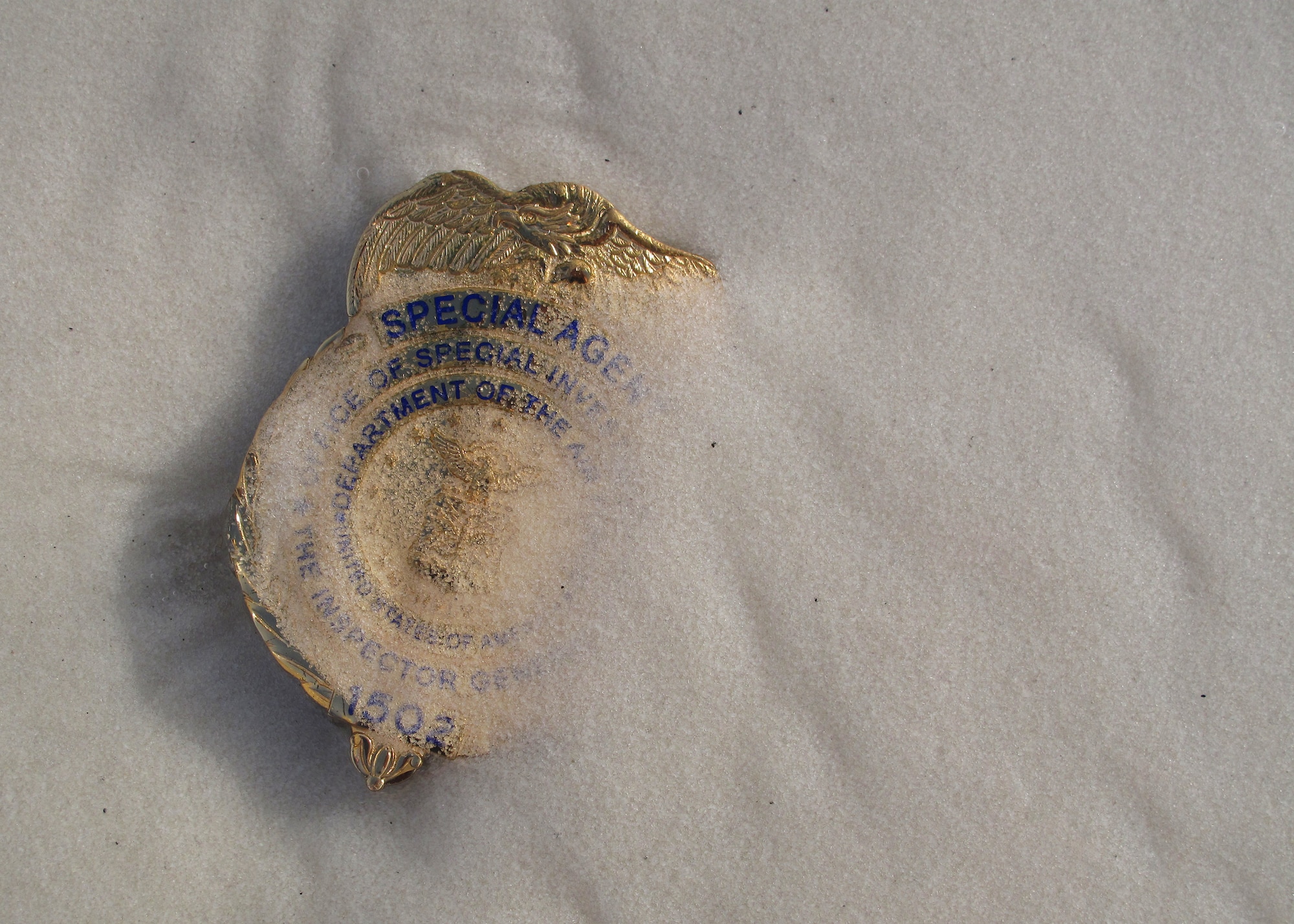 A photo of Maj. Adrianna Vorderbruggen’s badge in the sands along the Gulf of Mexico was taken by her commander, Lt. Col. Pamela Alley, 9th Field Investigations Squadron, on Christmas Day, only four days after Vorderbruggen’s death.  Special Agent Vorderbruggen was killed in action Dec. 21 while deployed to Bagram Airfield, Afghanistan.  (Courtesy photo) 