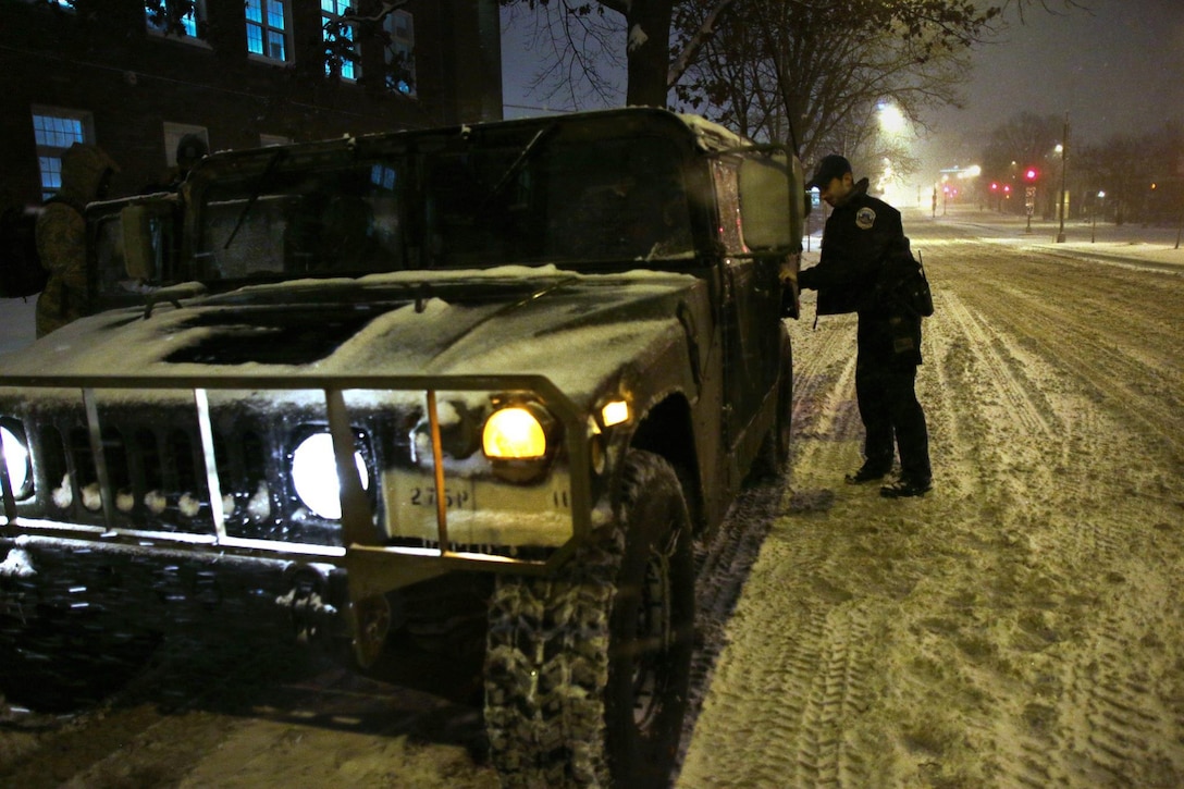A law enforcement officer works with service members providing transportation support during winter weather response operations in Washington, D.C., Jan. 22, 2016. Army National Guard photo by Sgt. Tyrone Williams