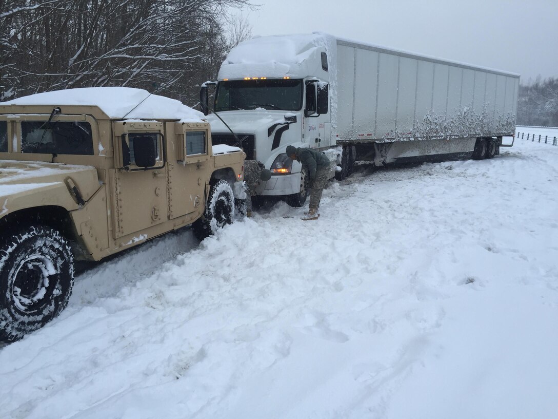 Soldiers supporting winter storm response operations connect towing chains to a semitruck stuck in snow on Interstate 75 south of Lexington, Ky., Jan. 23, 2016. Kentucky National Guard photo