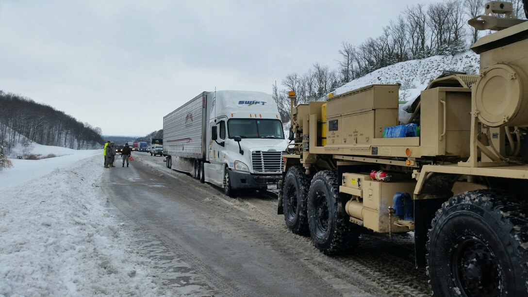 A soldier driving a heavy expanded mobility tactical truck pulls out a semitruck stuck in snow as fellow soldiers and civilian responders stand by during winter storm response operations on Interstate 75 south of Lexington, Ky., Jan. 23, 2016. The soldiers are assigned to the Kentucky National Guard’s 1149th Forward Support Company. Kentucky National Guard photo
