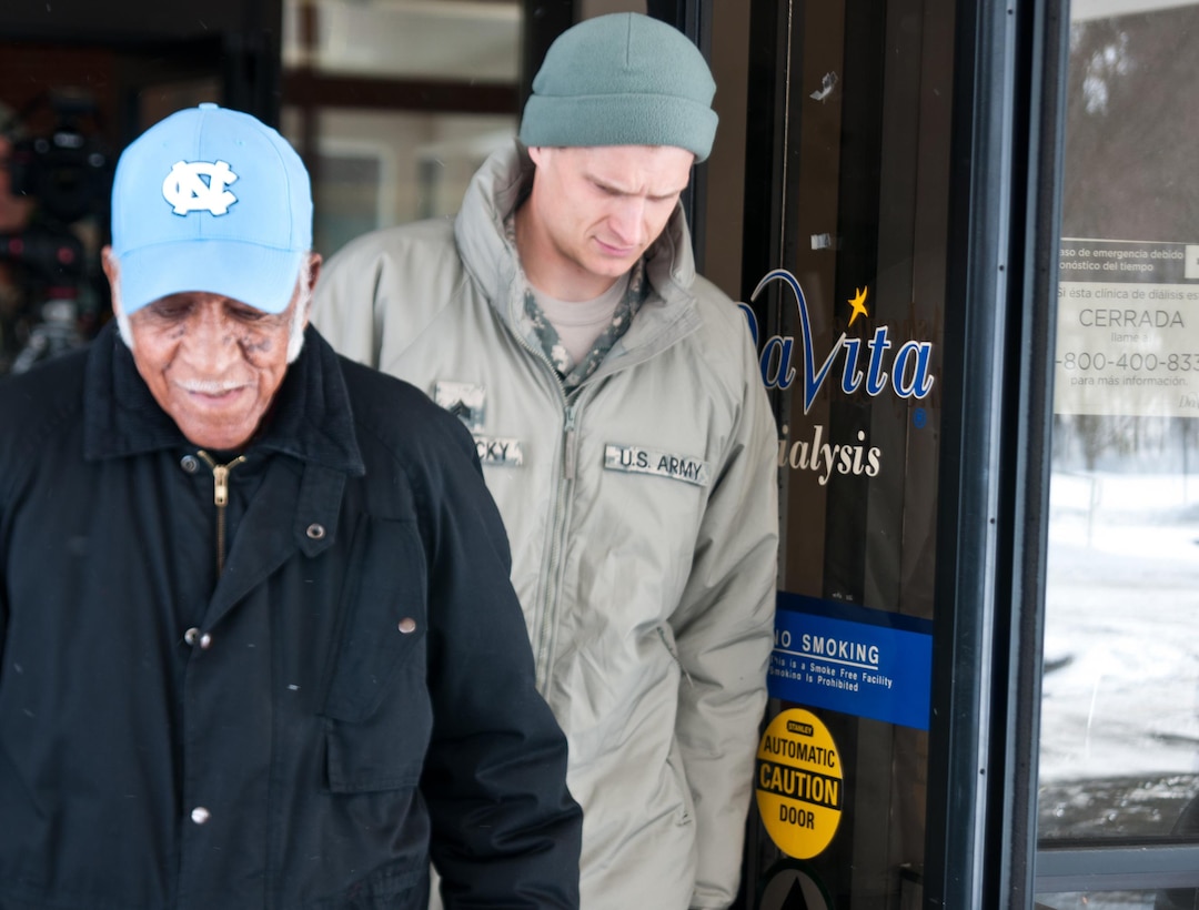 Army Sgt. Colin Kalescky, right, helps escort Charles Harbison, an 86-year-old resident of Asheville, N.C., as he exits Davita Kidney Care Center following his dialysis treatment Jan. 23, 2016. Kalescky is assigned to the North Carolina National Guard’s Headquarters Company, 105th Military Police Battalion. Harbison called 911 emergency after discovering there was no way for him to make it to the center due to the severe winter weather and because of the overwhelming volume of emergency responses in the region, the guard was called to assist and transport Harbison in the hazardous conditions. North Carolina National Guard photo Sgt. Brian Godette