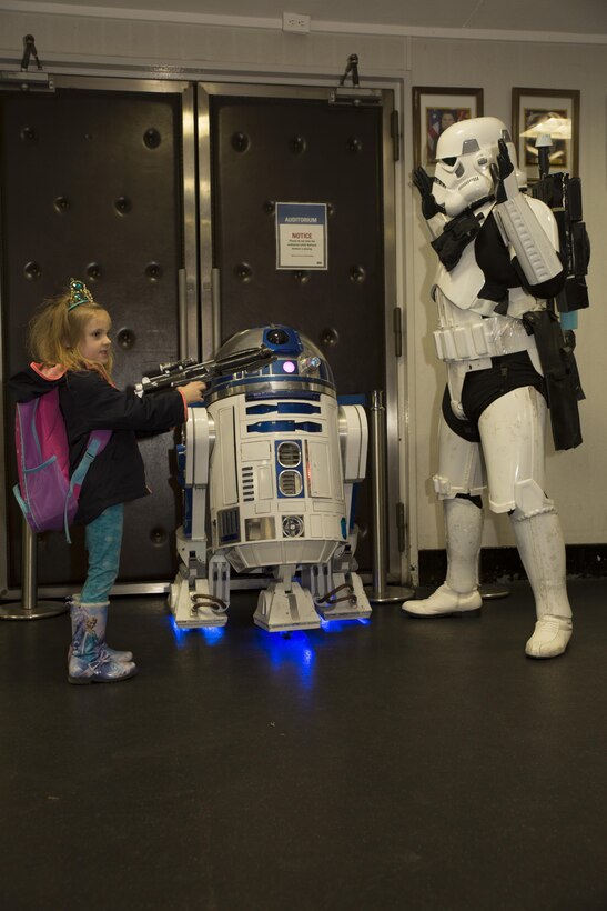 A station resident poses for a photo with R2-D2 and a stormtrooper at the Sakura Theater during a Star Wars: The Force Awakens promotion at Marine Corps Air Station Iwakuni, Japan, Jan. 17, 2016. Richard Inoue, dressed as the stormtrooper spent four years hand building his R2-D2 replica known as R2-J1 and is officially licensed. The promotion provided station residents the opportunity to interact and take group photos with both characters.