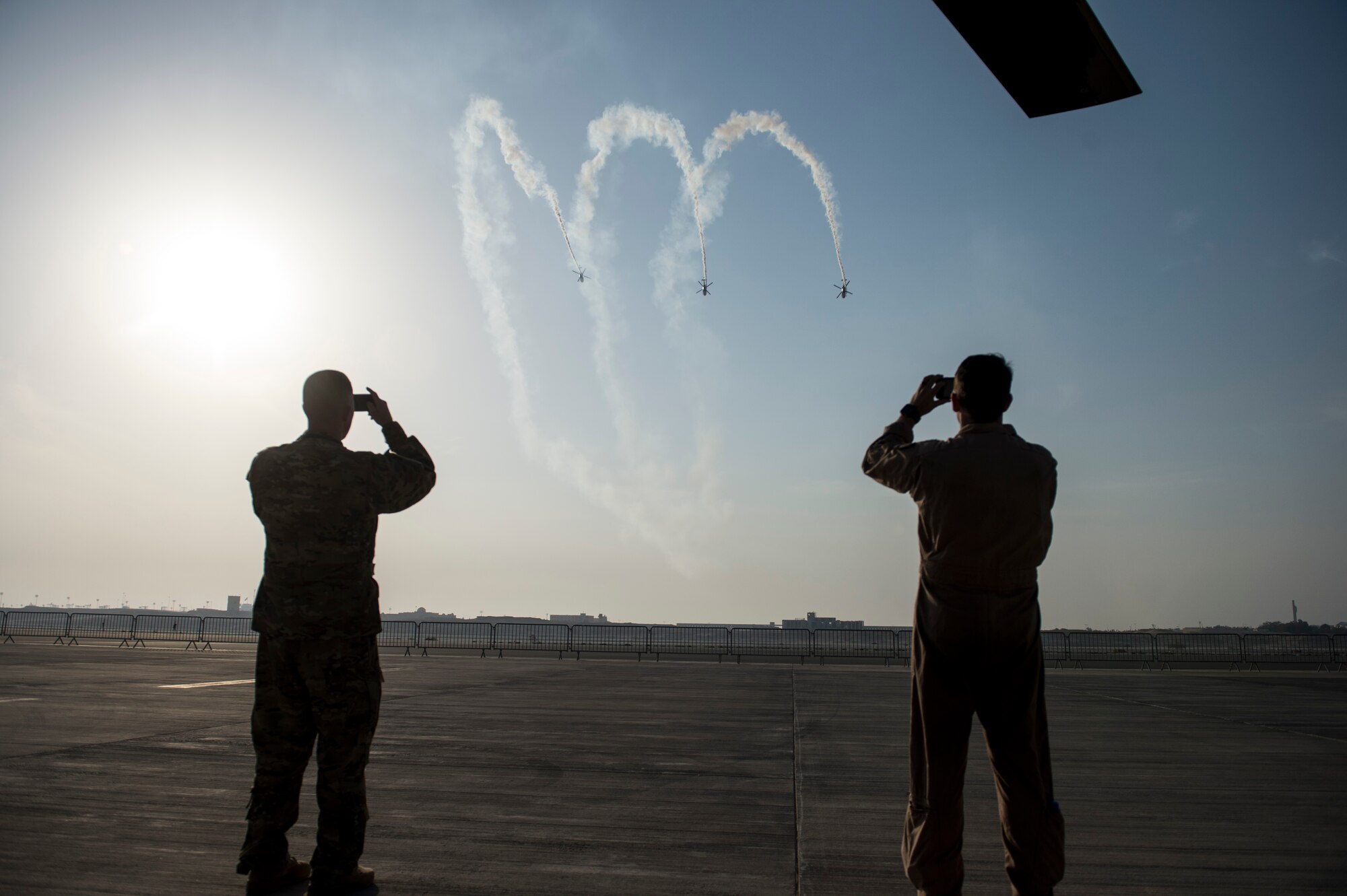 Members from the United States military record the Sarang Helicopter Display team during the Bahrain International Airshow at Sakhir Airbase in Manama, Bahrain, Jan. 21, 2016. The team flies four modified HAL Dhruv helicopters, also known as ALH (Advanced Light Helicopter). (U.S. Air Force photo by Staff Sgt. Corey Hook/Released)