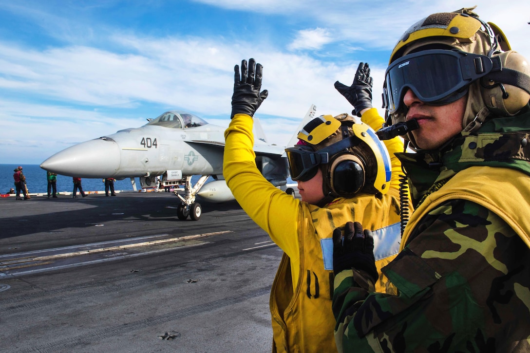 Navy Airman Molly McGuinness directs an F/A-18E Super Hornet onto a catapult on the flight deck while Petty Officer 1st Class Manuel Laguna supervises aboard the USS John C. Stennis in the Pacific Ocean, Jan 22, 2016. Laguna is an aviation boatswain’s mate. U.S. Navy photo by Petty Officer 3rd Class Kenneth Rodriguez Santiago